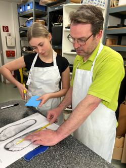 Ausbilder und Auszubildende beim Anzeichnen einer Einlage in der Werkstatt